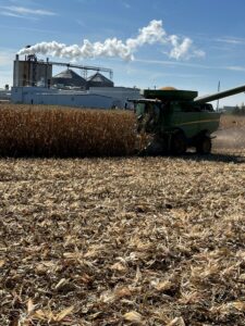 corn combine harvests in front of ethanol plant