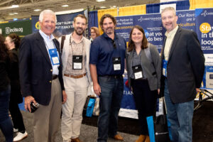 A diverse group of professionals standing together at a trade show, engaging in conversation and networking.