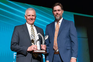 . Two men in suits and ties proudly holding an award, showcasing their achievement and professionalism.
