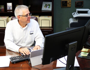 A man with glasses types on computer looking at the screen