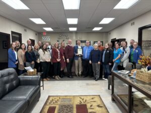 A cheerful gathering of people standing together, posing for a picture in a cozy indoor setting.