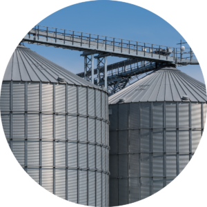 Two large grain silos stand against a clear blue sky, showcasing agricultural storage and a serene rural landscape.